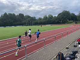 Vier Läufer auf einer Tartanbahn im Stadion beim Wettlaufen